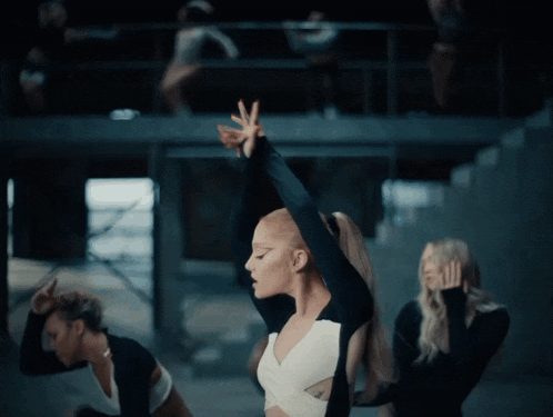 a woman in a black and white dress is dancing in a dark room