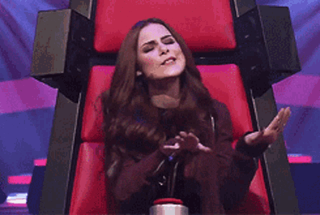 a woman is sitting in a red chair with her hands out