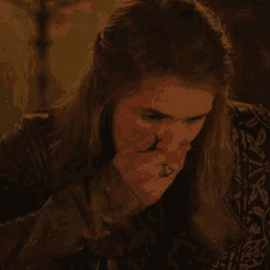 a woman with long hair and a ring on her finger covering her mouth