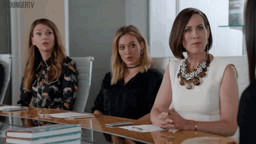 three women are sitting at a table with their hands folded in front of a screen that says youngertv