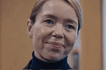a close up of a woman 's face with a turtleneck and earrings .