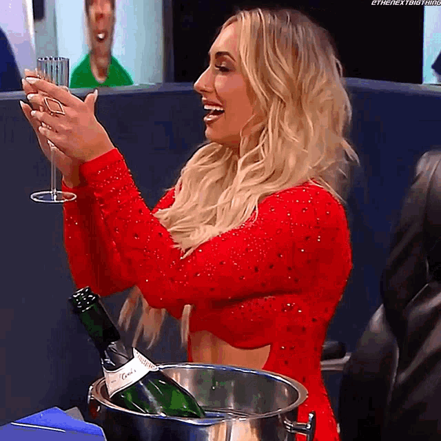 a woman in a red dress is holding a glass and a bottle of champagne in a bucket