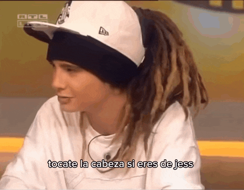 a man with dreadlocks wearing a hat and a white shirt says tocate la cabeza si eres de jess