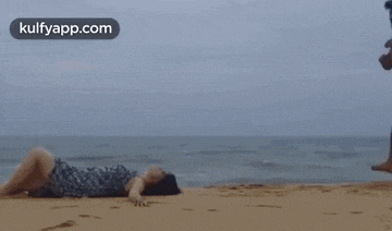 a man and a woman are kissing in the sand on a beach .