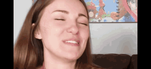 a close up of a woman 's face with her eyes closed and a painting in the background .