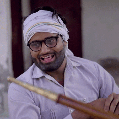 a man wearing glasses and a bandana on his head is smiling