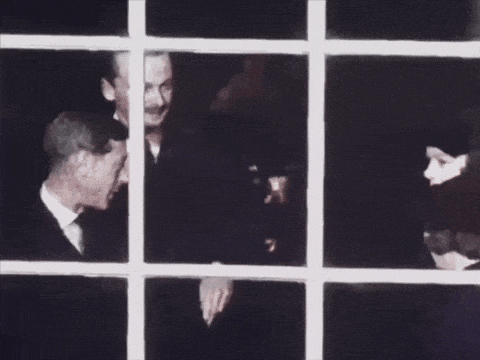 a man in a suit and tie is talking to another man