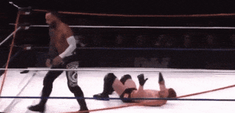 two men are wrestling in a ring with one laying on the ground .