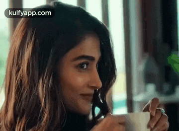 a woman is drinking a cup of coffee from a cup .