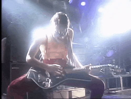 a man is playing a guitar on stage in front of a crowd .