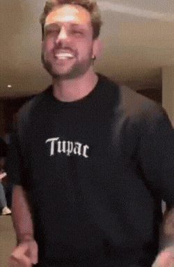 a man wearing a tupac shirt is smiling