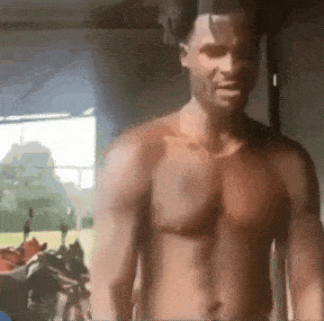 a shirtless man is standing in a room with a window .