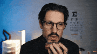 a man brushes his beard with a brush in front of an eye chart