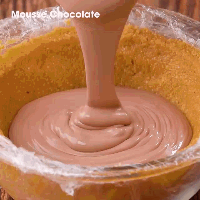 a bowl of mousse chocolate is being poured into a pie crust .