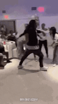 a group of people are dancing in a room with tables and chairs .