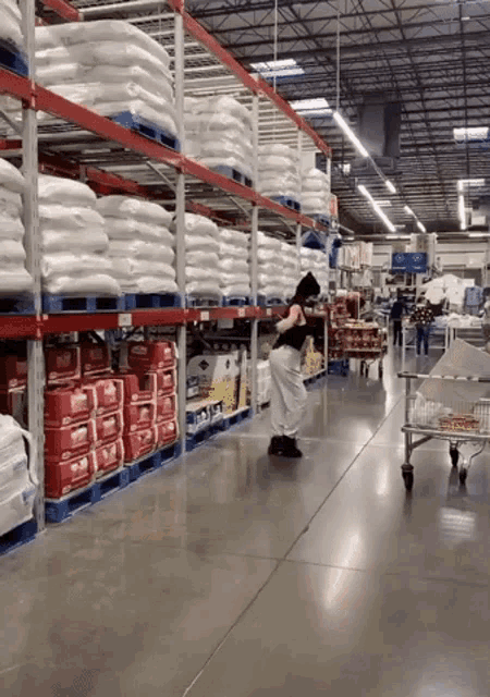 a woman is standing in a warehouse looking at a stack of boxes that say ' kirkland ' on them