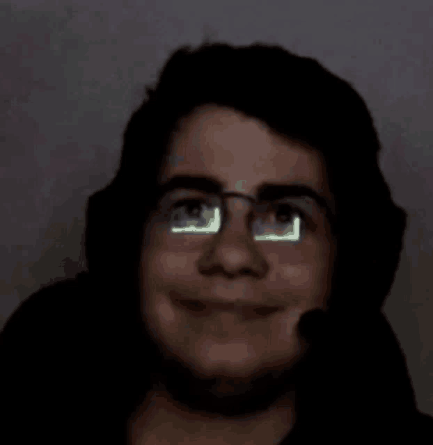 a man wearing glasses and headphones is smiling in the dark .