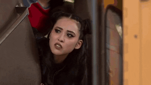a woman is sitting in the back of a school bus looking at the camera .