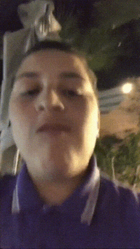 a man in a purple shirt is making a funny face