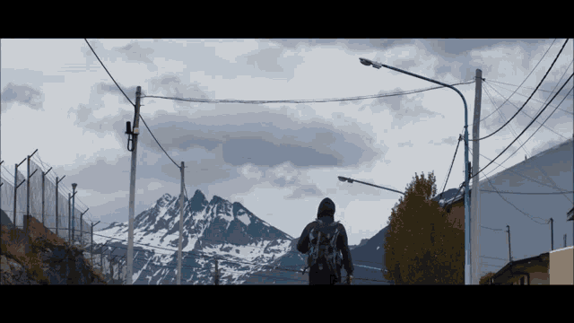 a person with a backpack is walking down a street with a mountain in the background