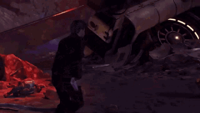 a man in a black jacket is standing in front of a destroyed car