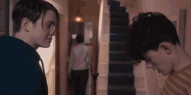 two young boys are standing next to each other in a hallway .