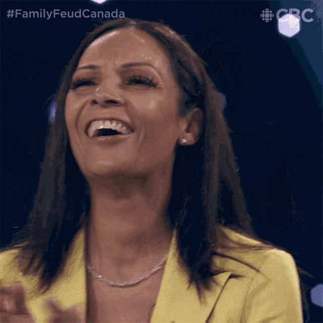 a woman in a yellow jacket is laughing with the hashtag familyfeudcanada
