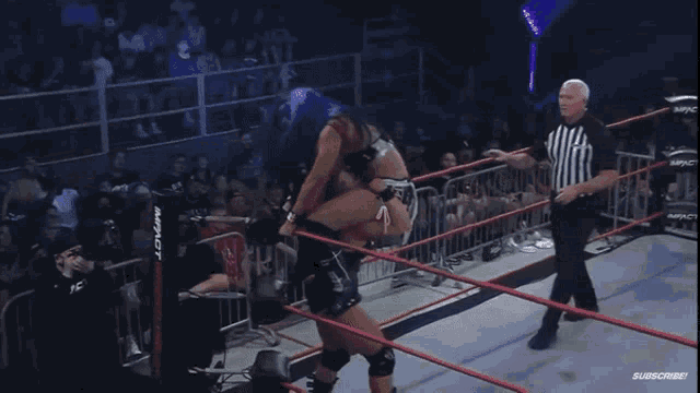 a wrestler with blue hair is laying on the floor in a ring