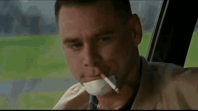 a man with a bandaged mouth is smoking a cigarette in a car .