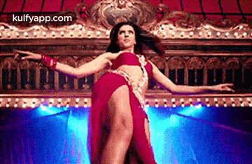 a woman in a red dress is dancing on a stage in front of a curtain .