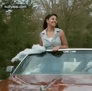 a woman is cleaning the windshield of a car with a cloth .