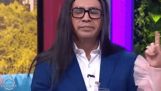 a man with long hair is wearing glasses and a blue suit