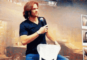 a man is sitting on a chair holding a microphone and talking into it .