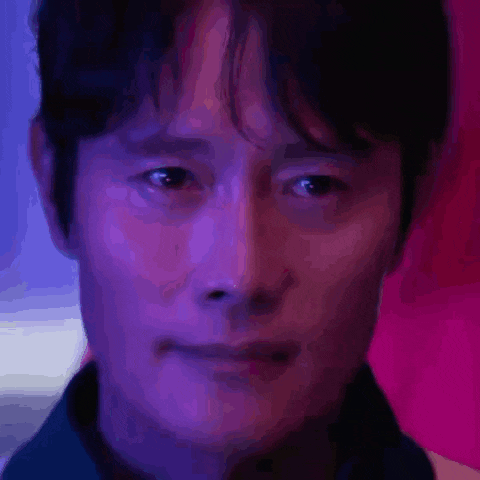 a close up of a man 's face with purple and blue lights behind him .