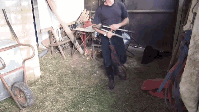 a man standing in a shed holding a pair of tongs