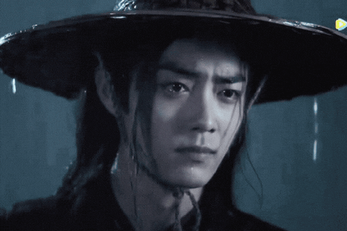 a man with long hair wearing a black hat
