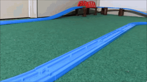 a toy train is going down a track on a green carpet .