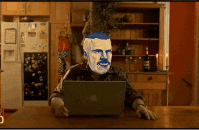 a man sitting at a table with an apple laptop in front of him