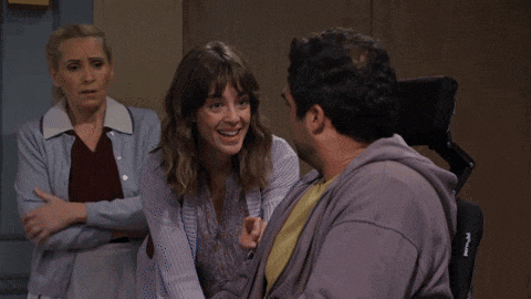 a man in a purple hoodie is smiling while talking to a woman