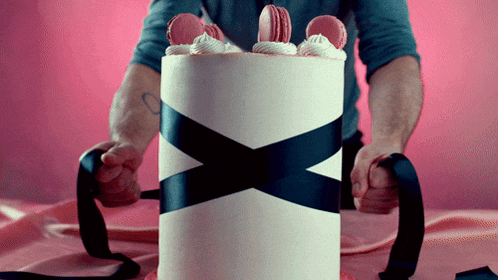 a man is holding a cake that has a black and white ribbon around it