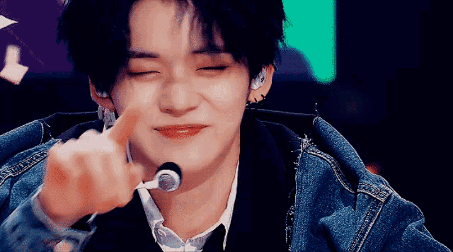a young man wearing a denim jacket and tie is giving the middle finger