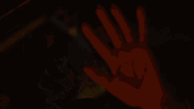 a blurred image of a person standing in a dark room with a yellow light behind them