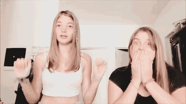 two young girls are dancing together in a room and one is wearing a choker .