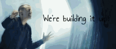 a man is standing in front of a window with the words " we 're building it up " written above him