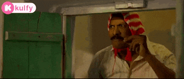 a man with a red and white scarf on his head is standing in front of a green door .