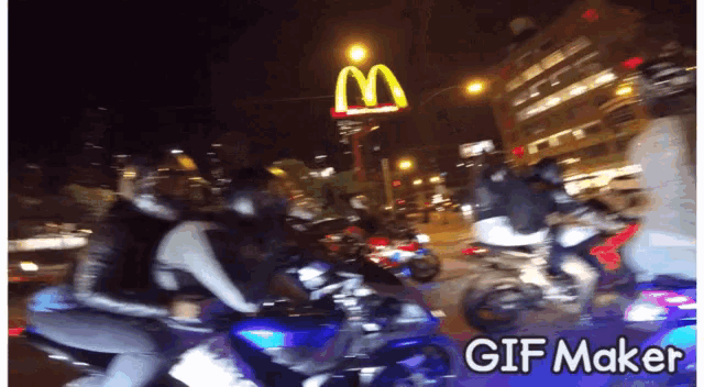 a blurry picture of people riding motorcycles with a mcdonald 's sign in the background