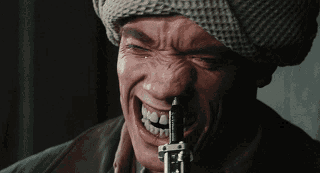 a close up of a man holding a gun with his mouth open