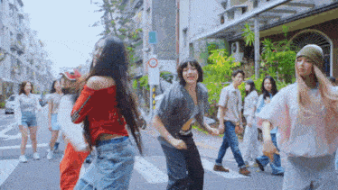 a group of people are dancing on a street with a no parking sign
