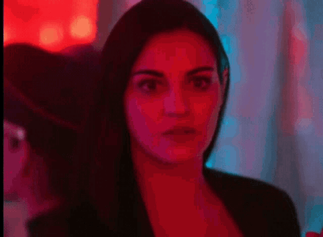 a woman is standing in front of a red and blue light .