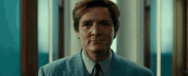 a man in a suit and tie is looking at the camera .
